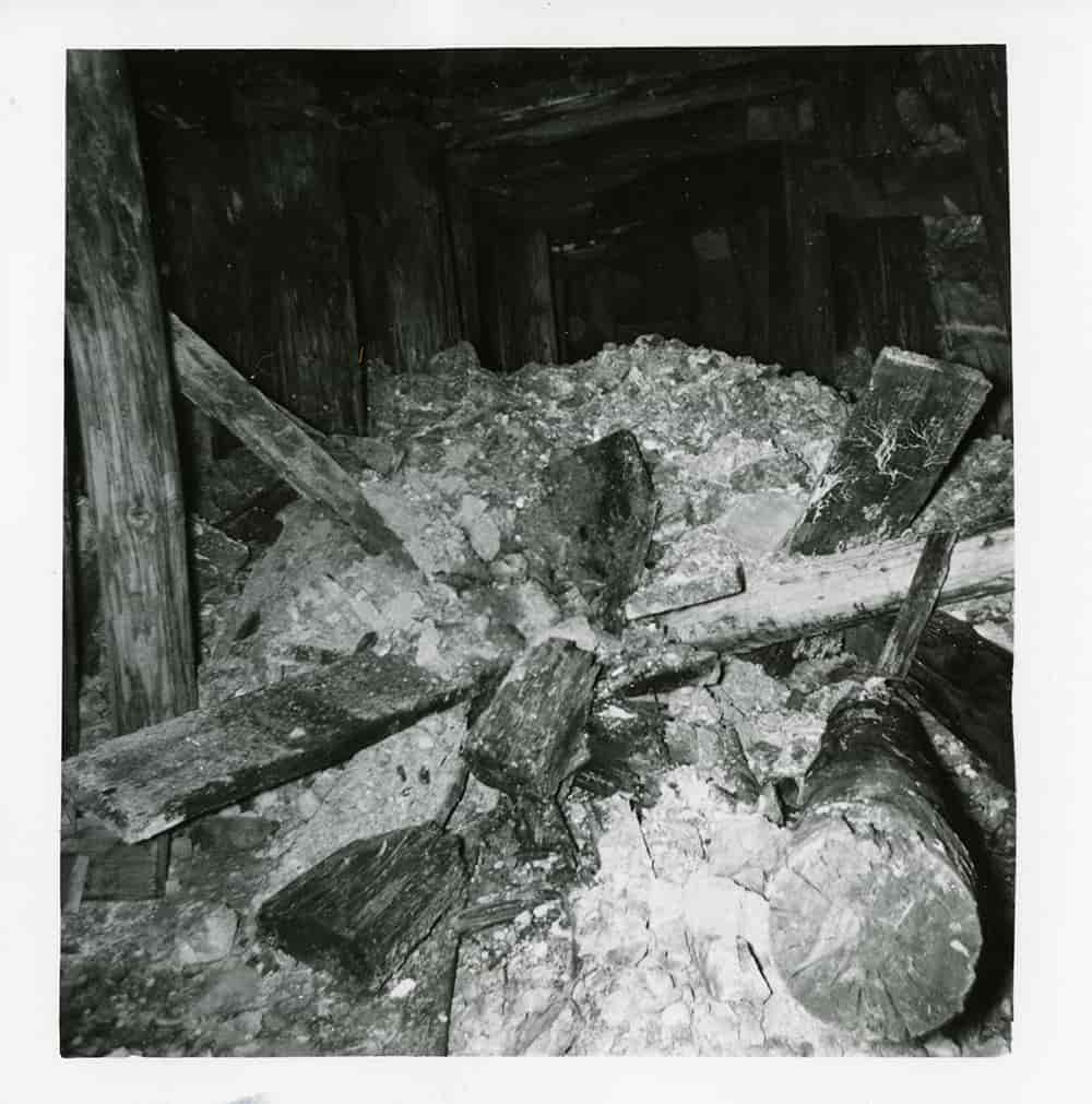 Black and white photograph of timbers and debris in a mine tunnel.
